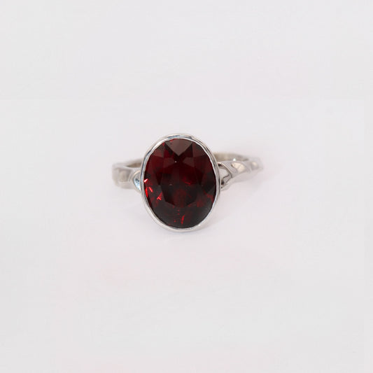 Silver ring with a red gemstone on a white background