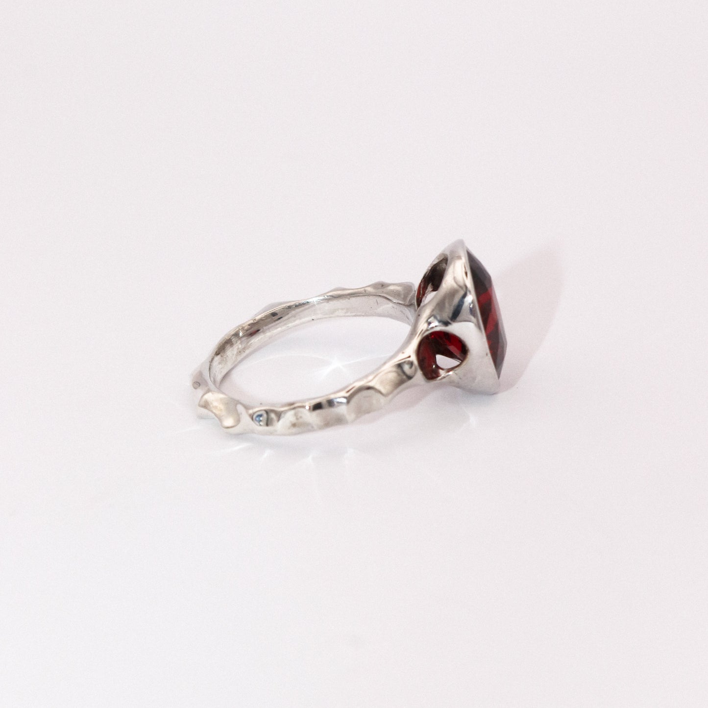 Silver ring with a red gemstone on a white background