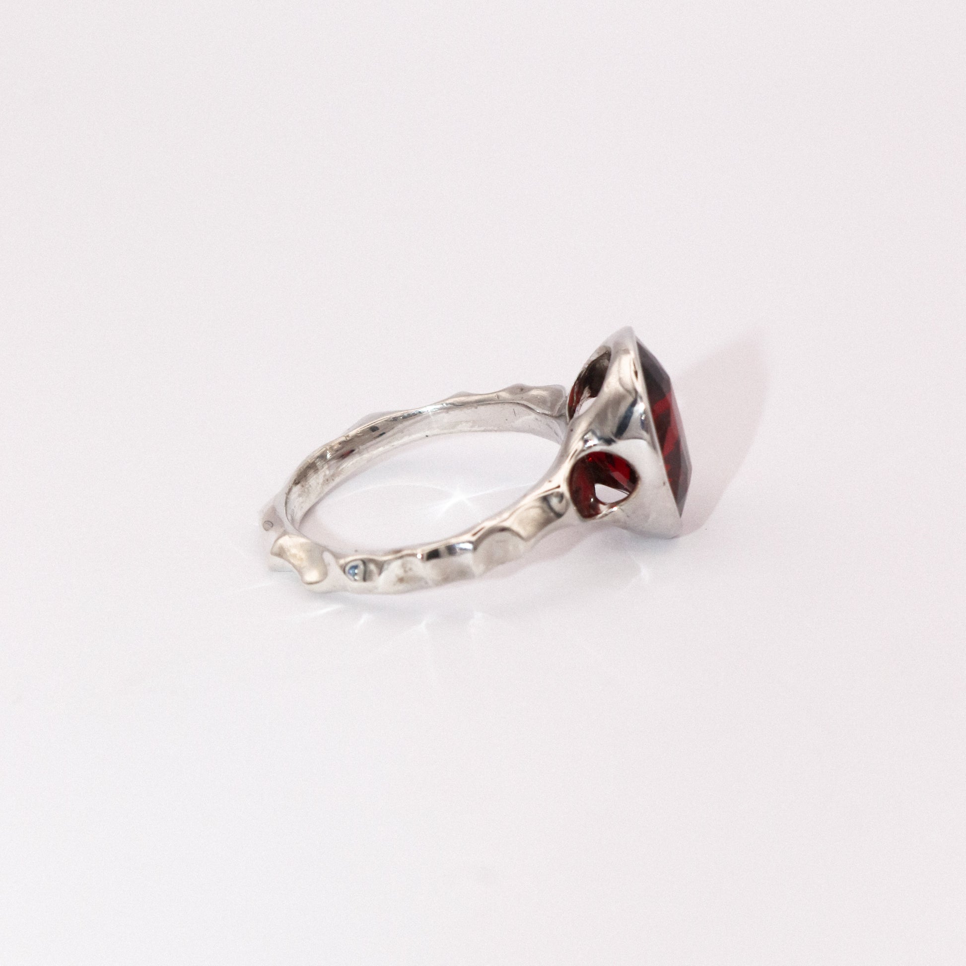 Silver ring with a red gemstone on a white background
