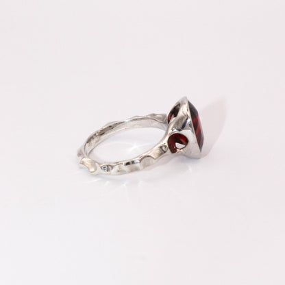 Silver ring with a red gemstone on a white background