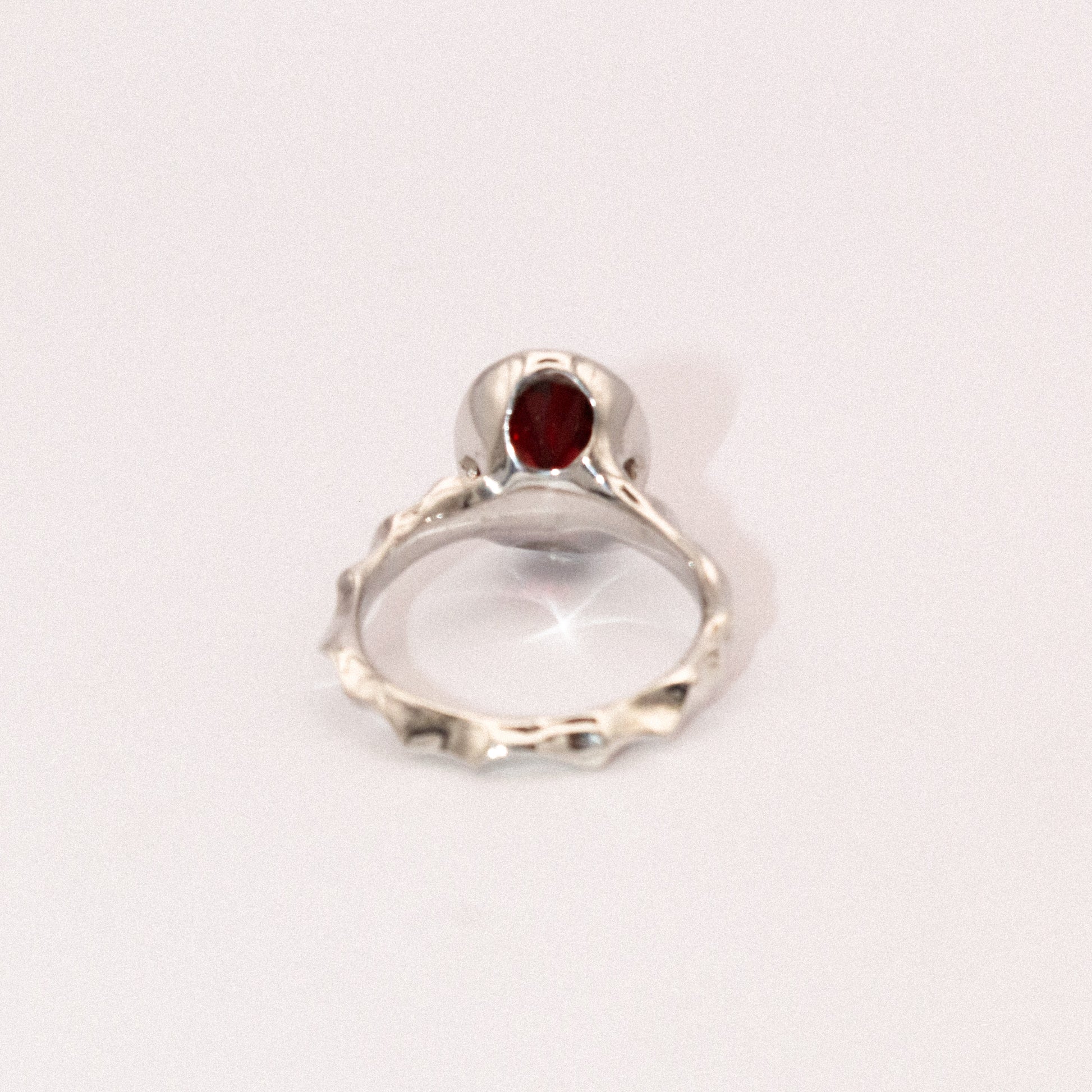 Silver ring with a red gemstone on a white background