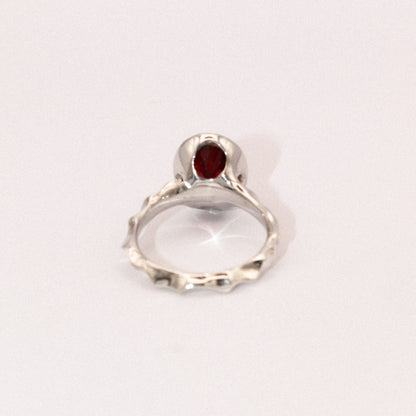 Silver ring with a red gemstone on a white background