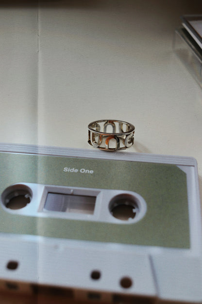 Silver ring on a vintage cassette tape with 'Side One' text.