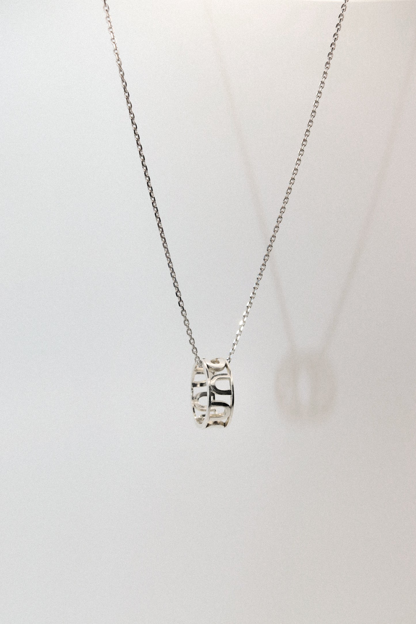 Silver necklace with a pendant on a light gray background