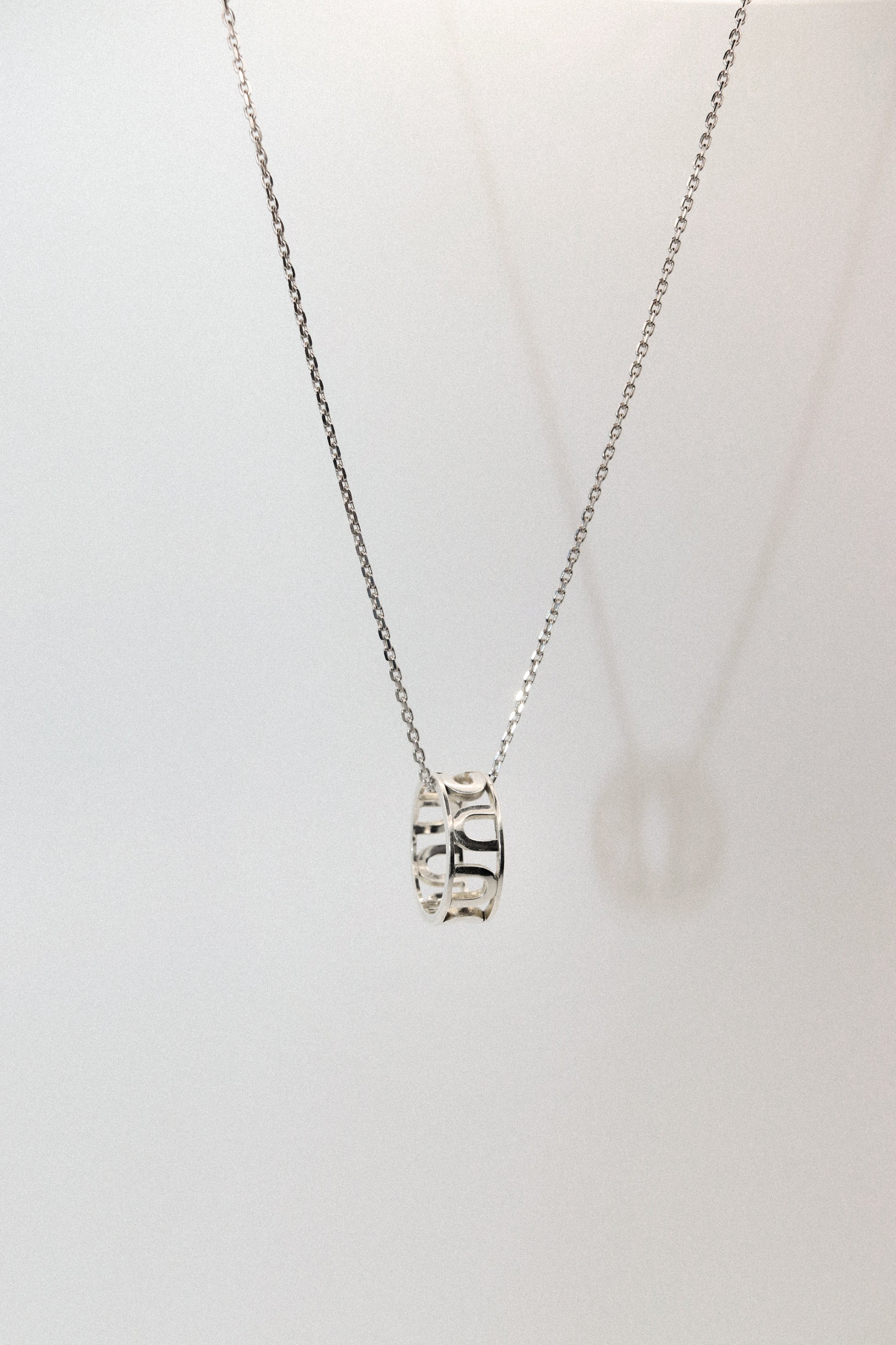 Silver necklace with a pendant on a light gray background