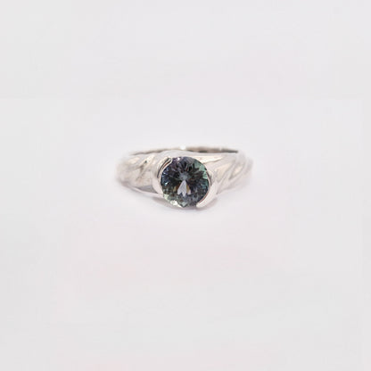 Silver ring with a dark gemstone on a light gray background
