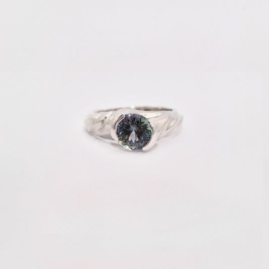 Silver ring with a dark gemstone on a light gray background
