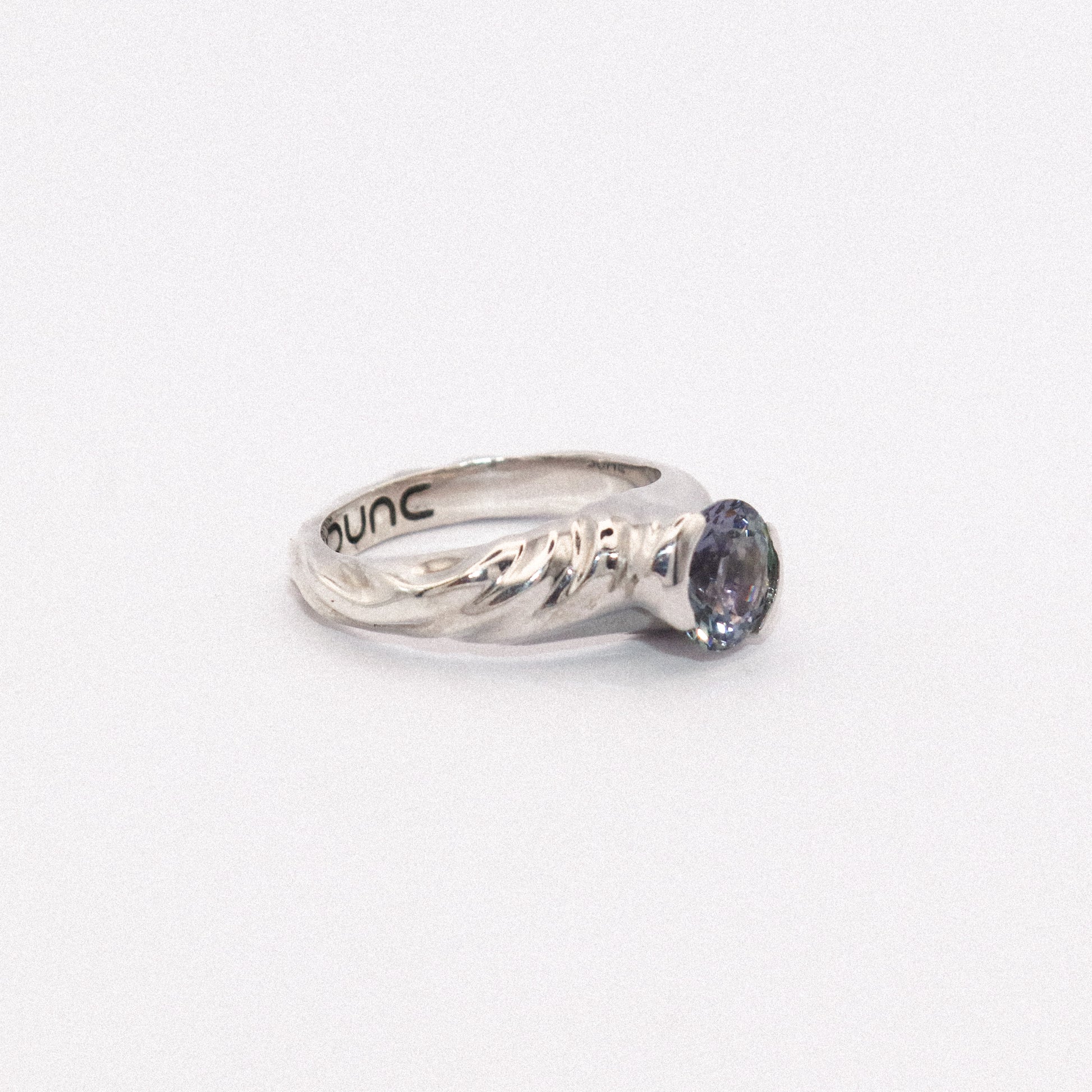 Silver ring with a purple gemstone on a white background