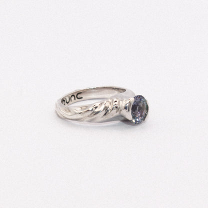 Silver ring with a purple gemstone on a white background