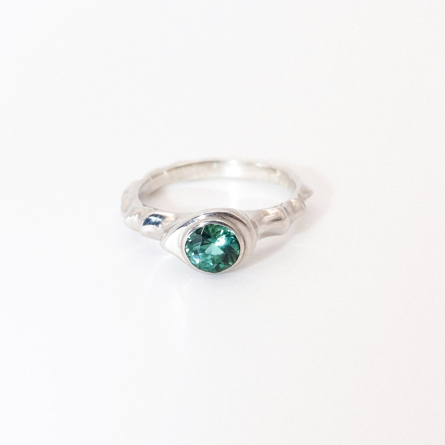 Silver ring with a green gemstone on a white background