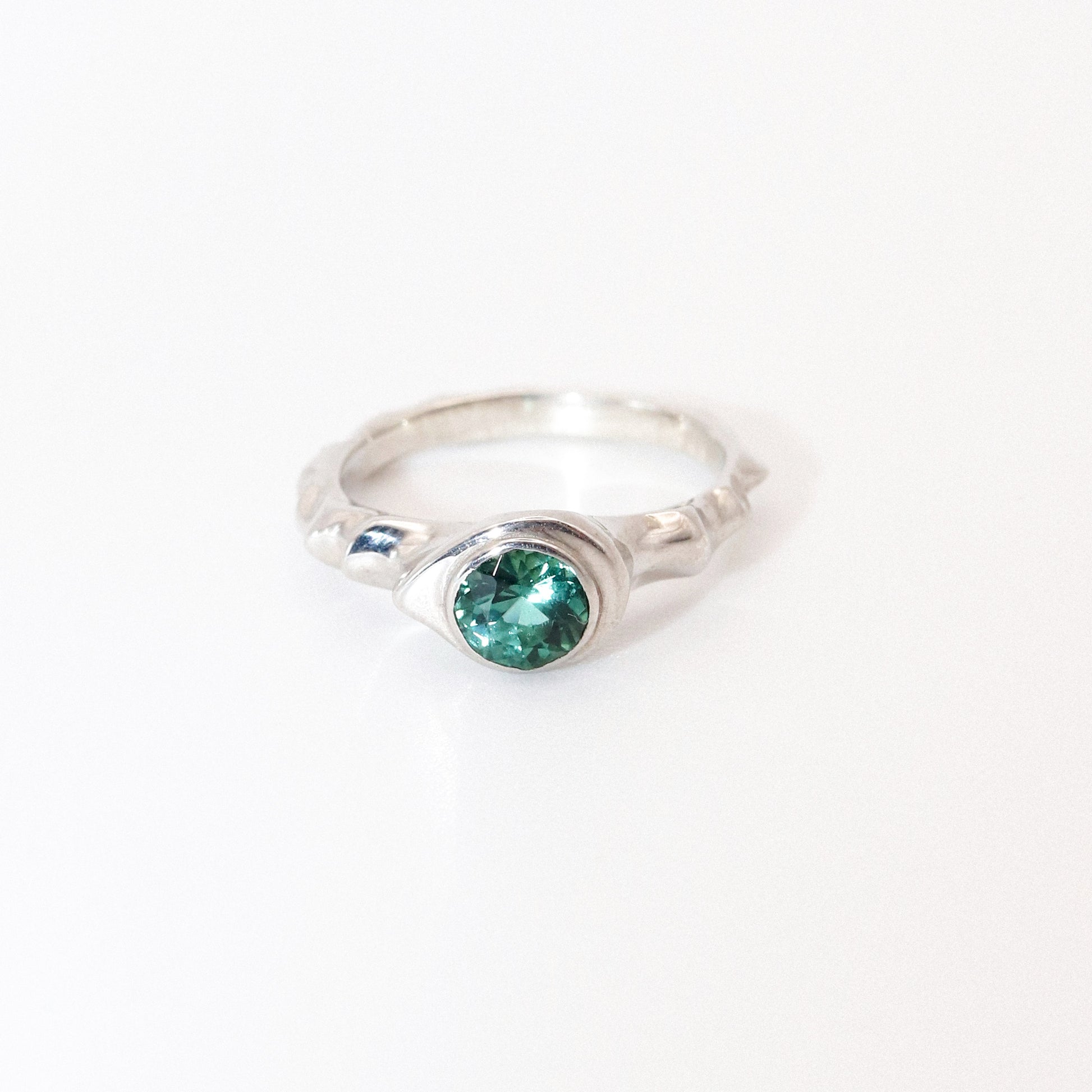 Silver ring with a green gemstone on a white background