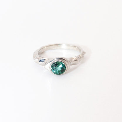 Silver ring with a green gemstone on a white background