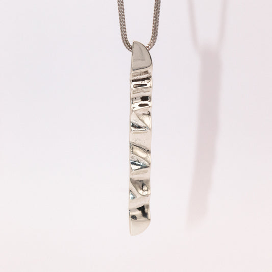 Silver necklace with a unique pendant on a light pink background