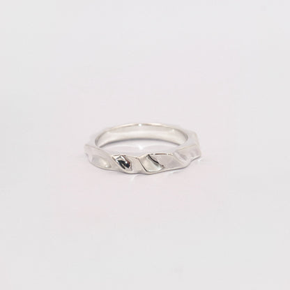 Silver ring with a textured design on a light gray background