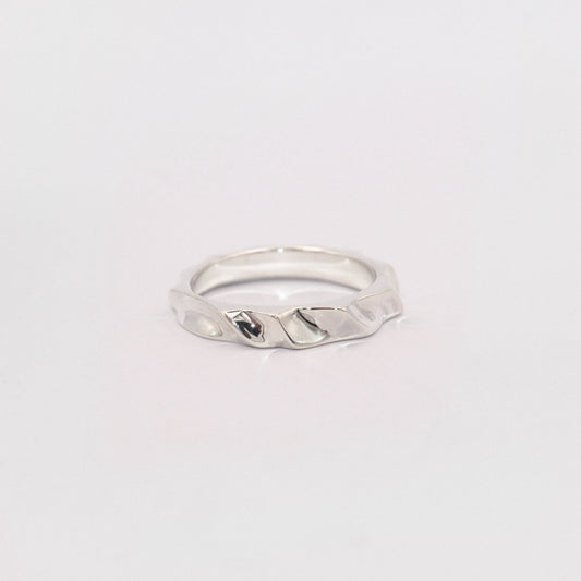 Silver ring with a textured design on a light gray background