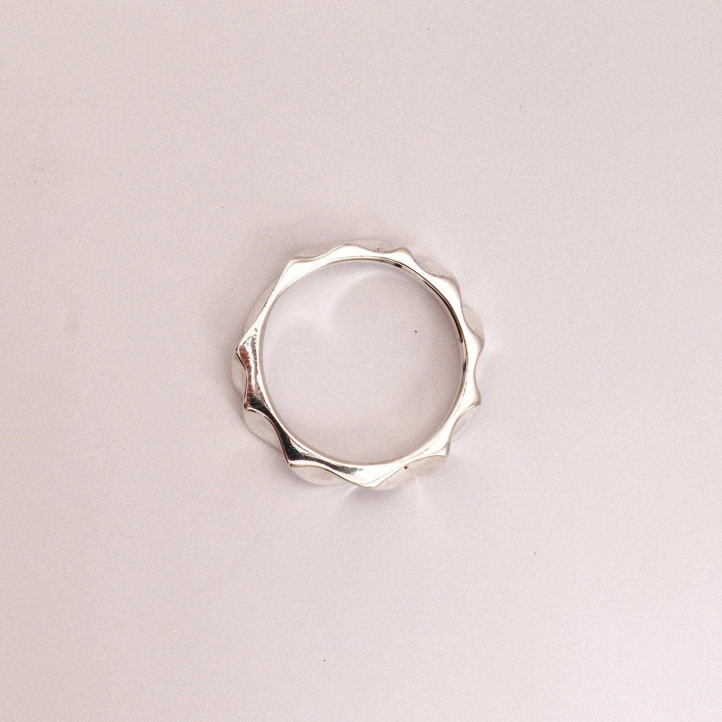 Silver ring with a unique design on a light pink background