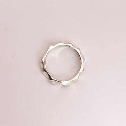 Silver ring with a unique design on a light pink background