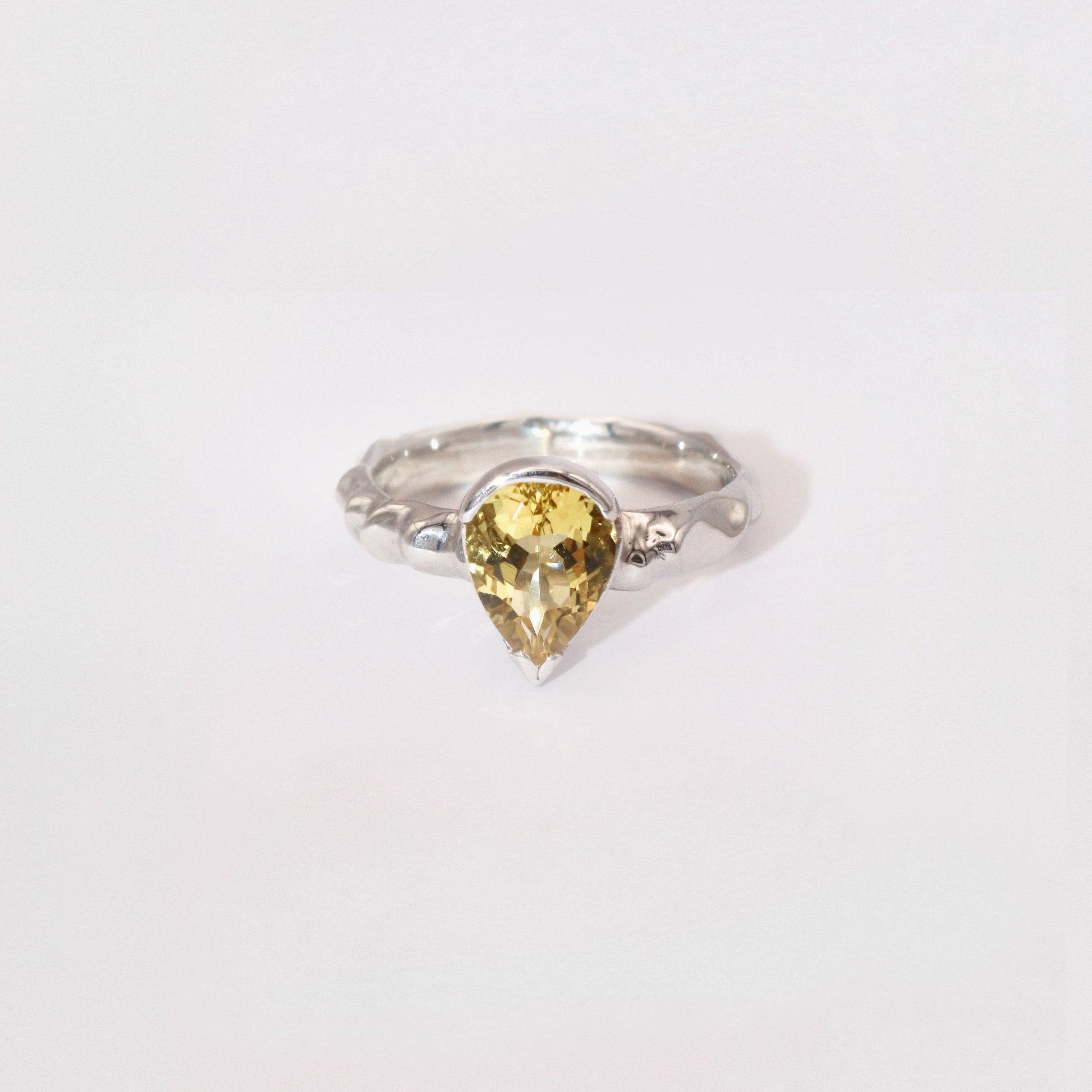Silver ring with a yellow gemstone on a white background