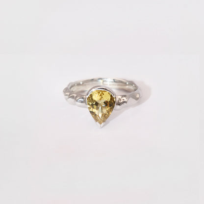 Silver ring with a yellow gemstone on a white background