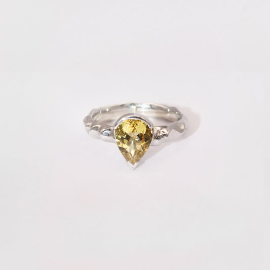 Silver ring with a yellow gemstone on a white background