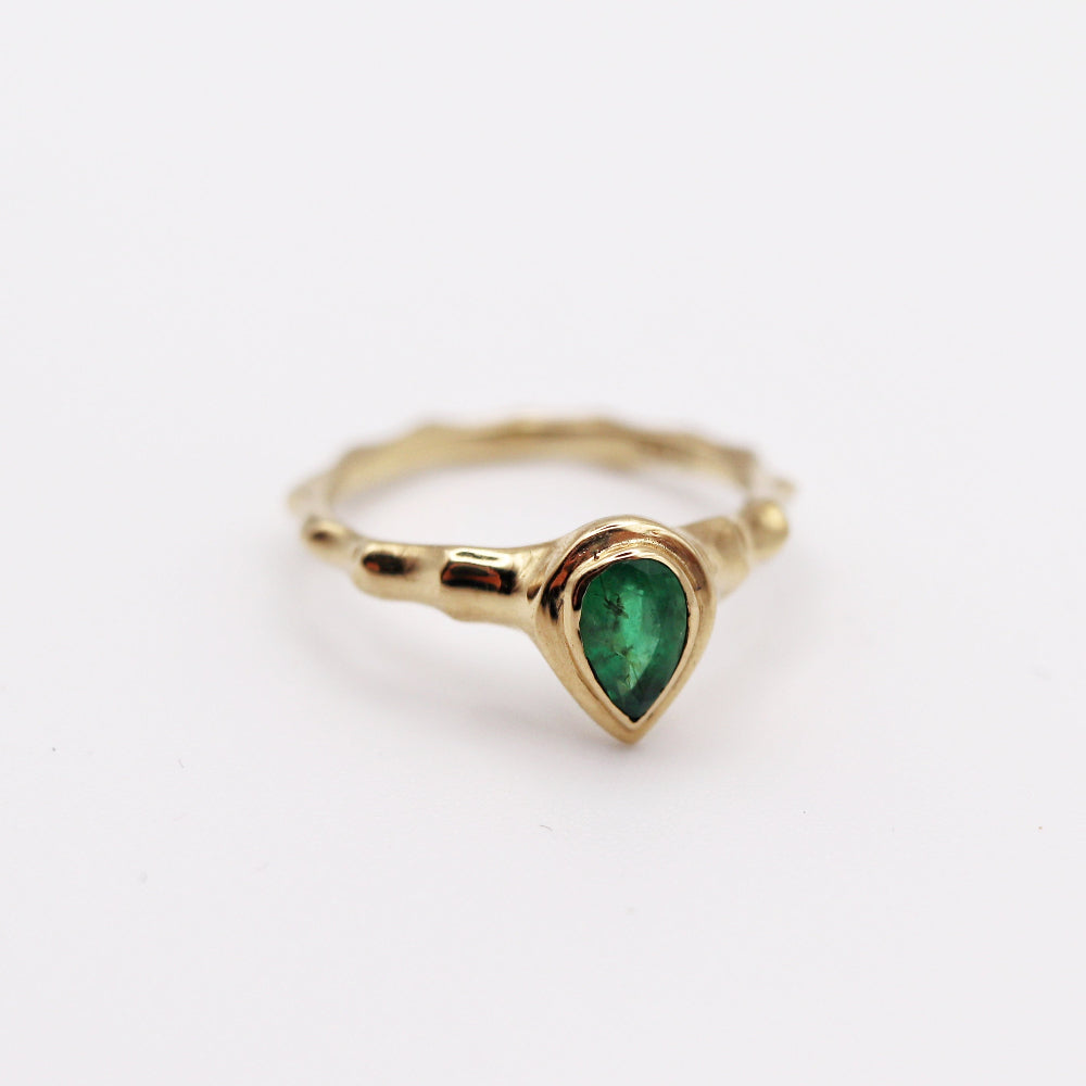 Gold ring with a green gemstone on a white background