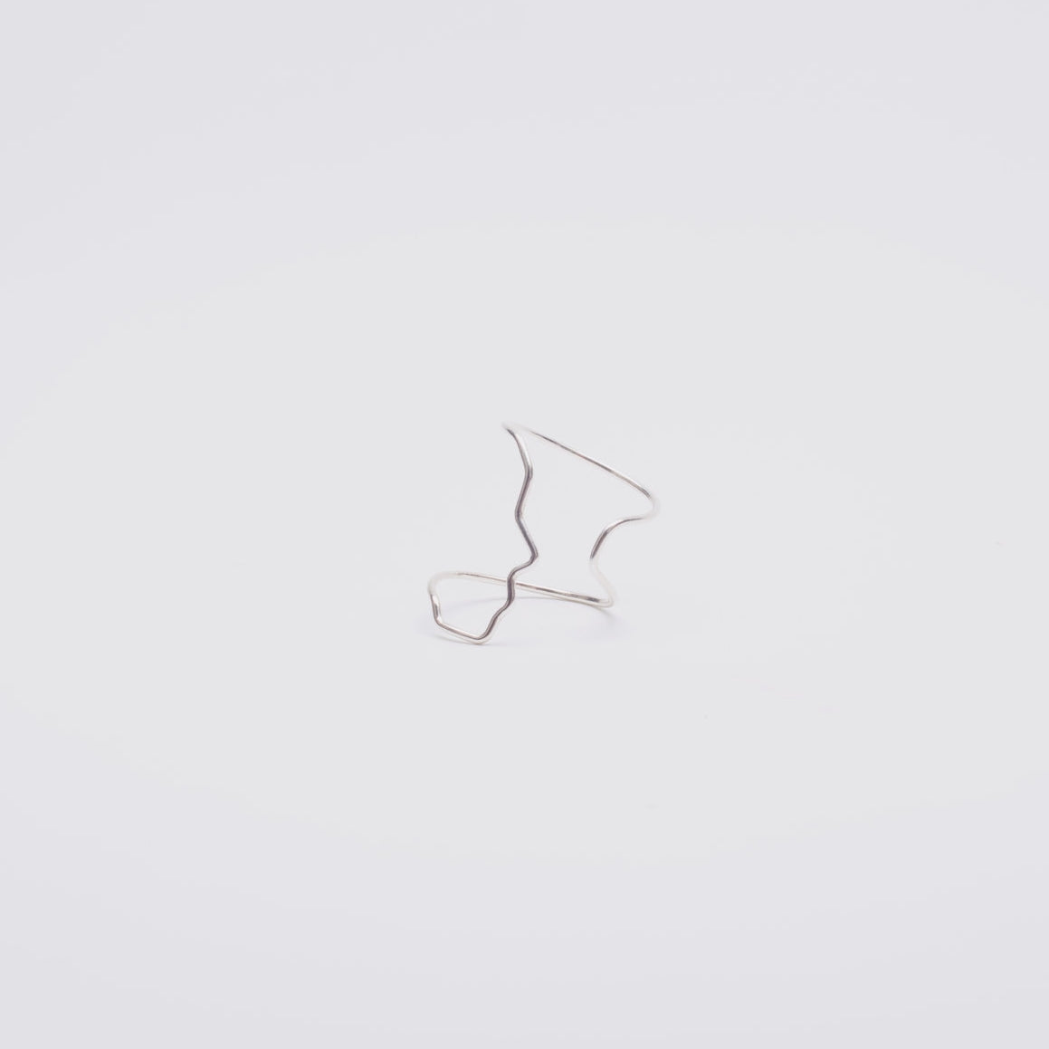 Small silver face profile ring on a light gray background
