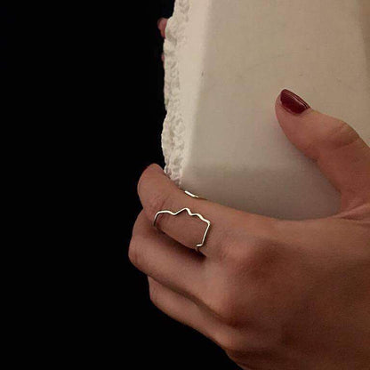 Hand wearing a silver ring holding a white candle against a black background