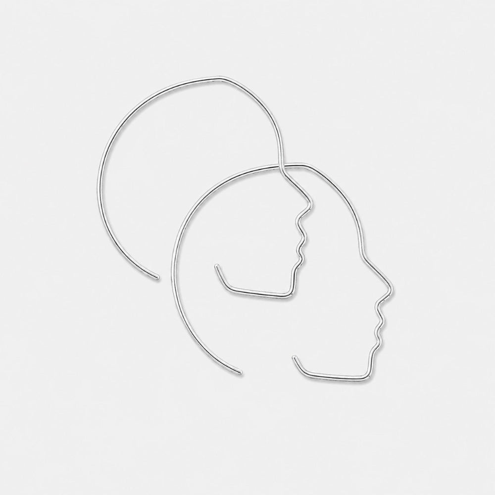 Silver hoop earrings with profile designs on a light gray background