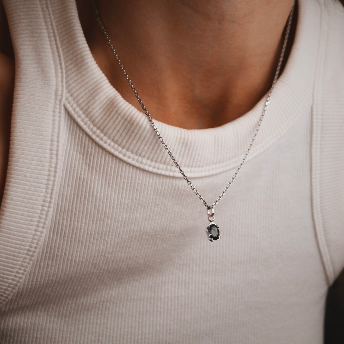 Purple spinel pendant worn on a white shirt