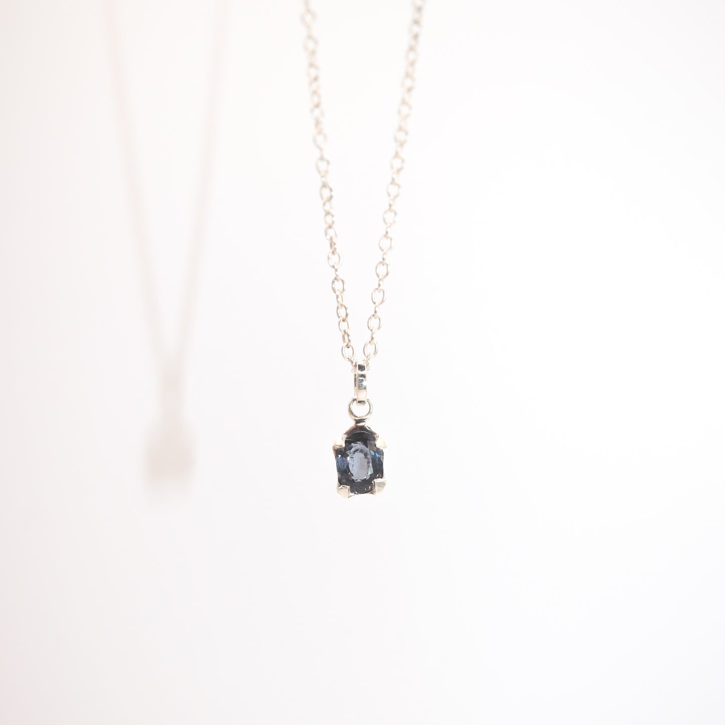 Necklace with a pendant featuring a blue gemstone on a white background