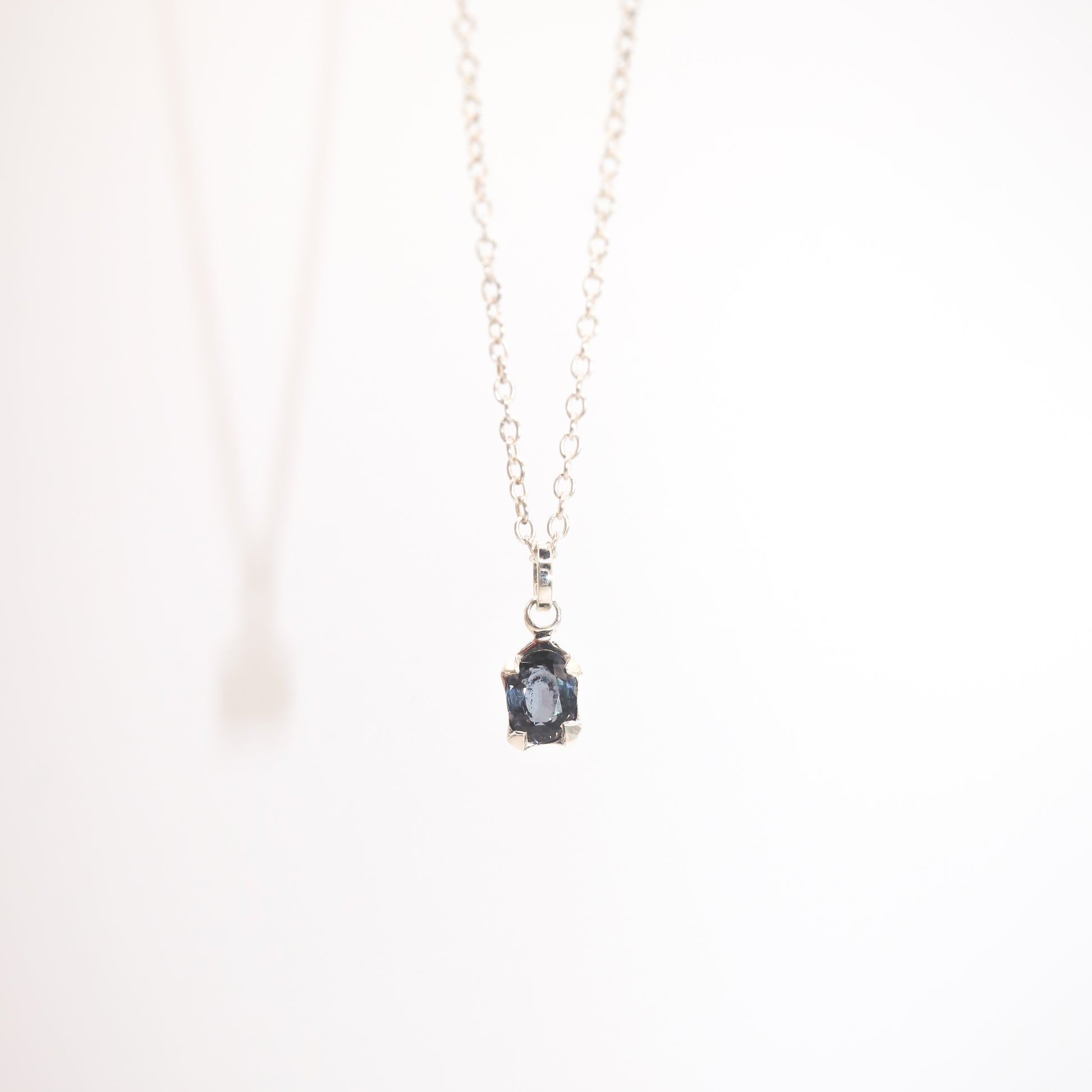 Necklace with a pendant featuring a blue gemstone on a white background