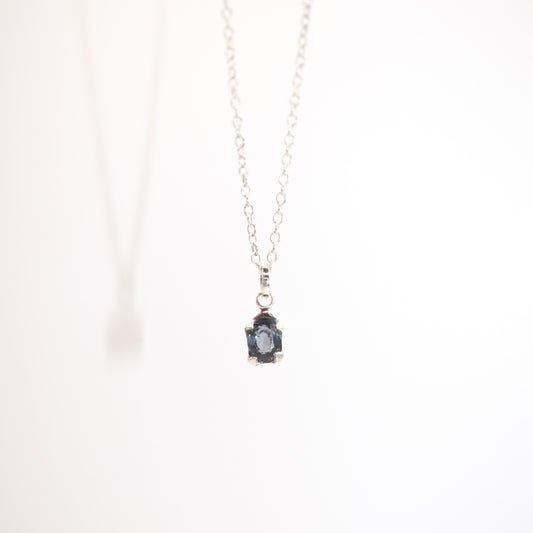 Necklace with a pendant featuring a blue gemstone on a white background