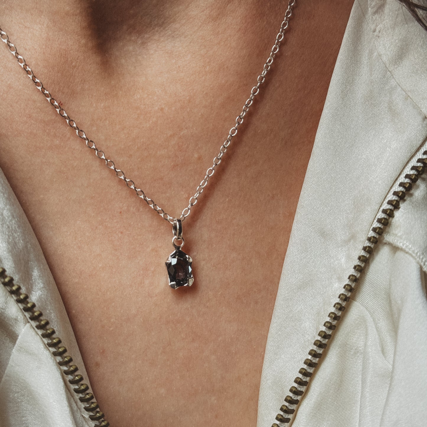 Necklace with a pendant worn by a person, close-up on skin