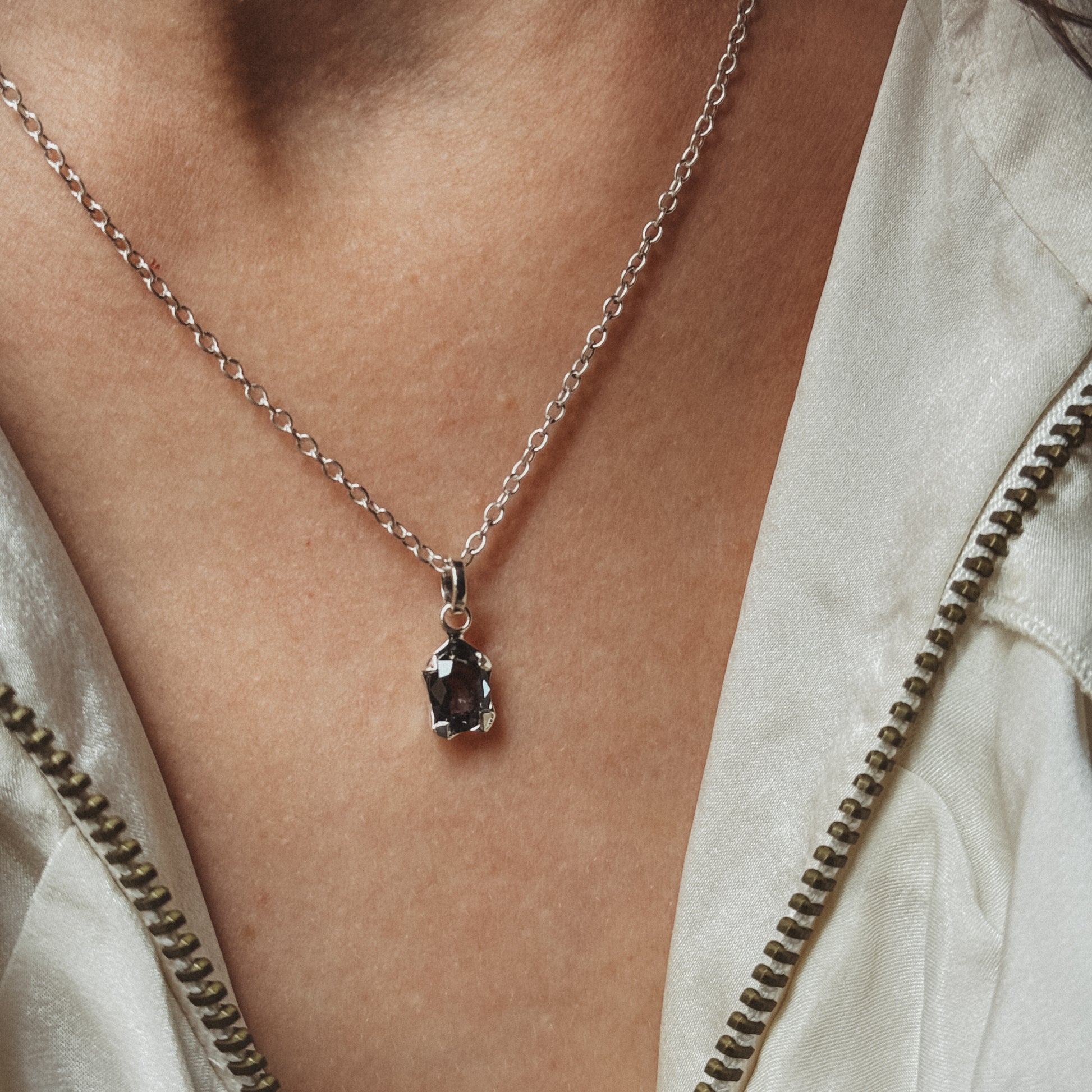 Necklace with a pendant worn by a person, close-up on skin