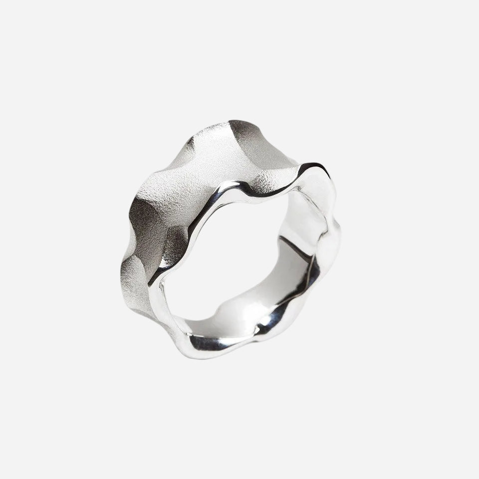 Silver ring with a wavy design on a white background