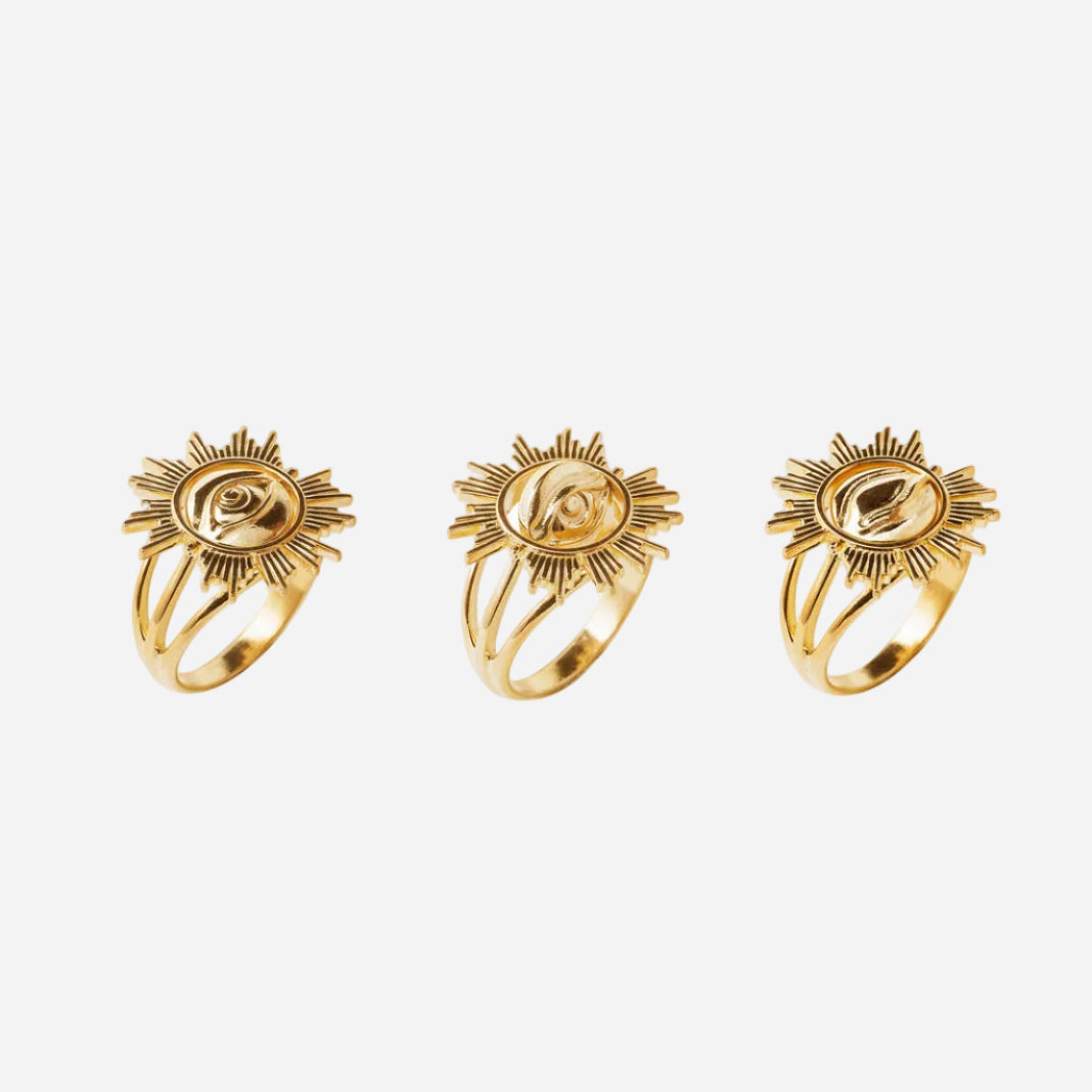 Three gold rings with sun design on a white background
