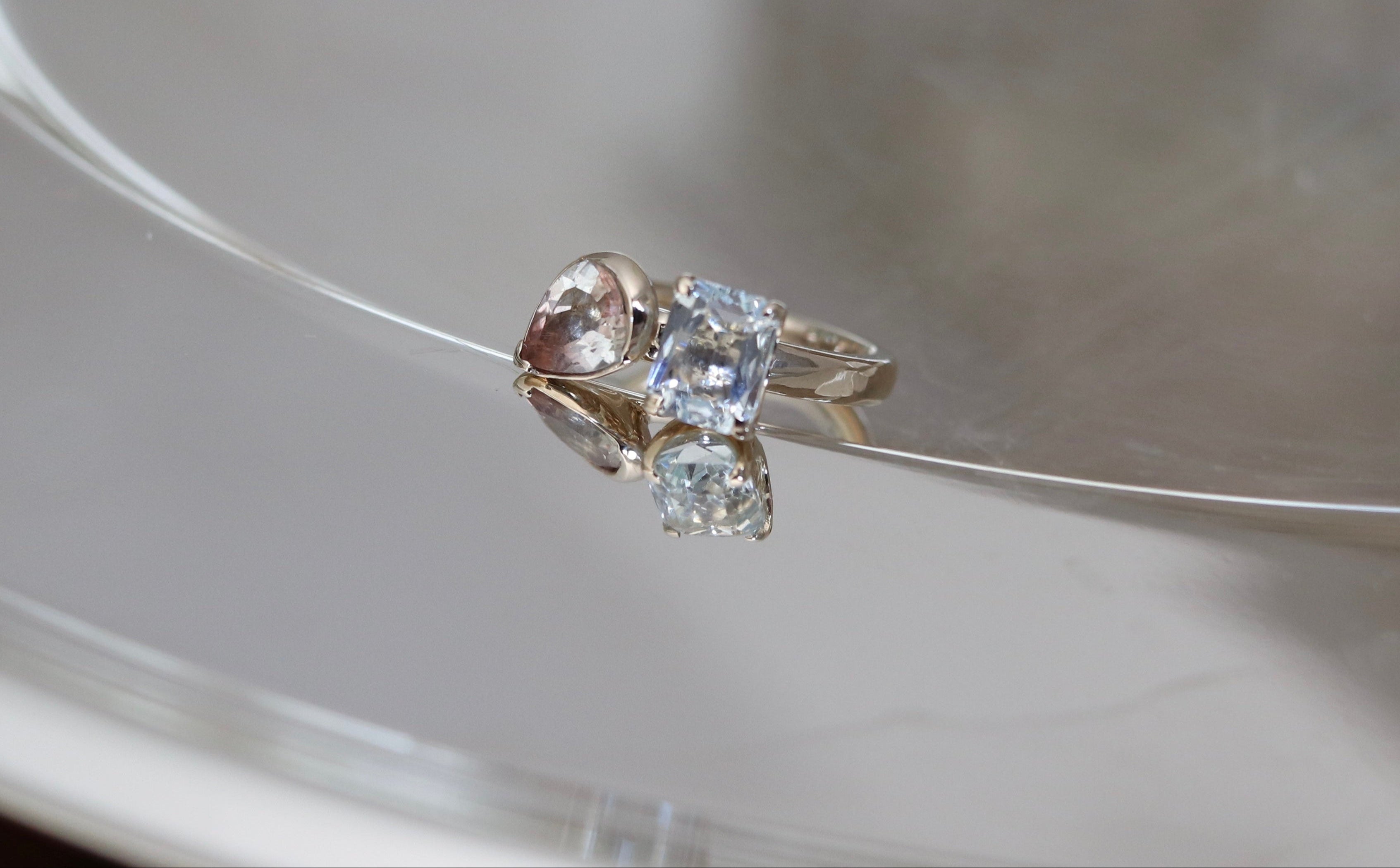 Ring with heart-shaped center stone and smaller round stones on a reflective surface