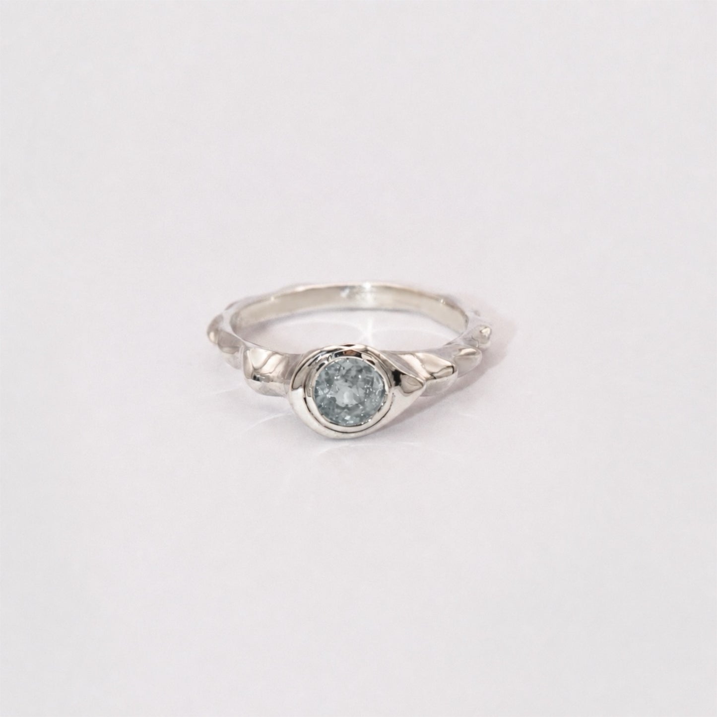 Silver ring with a light blue gemstone on a white background