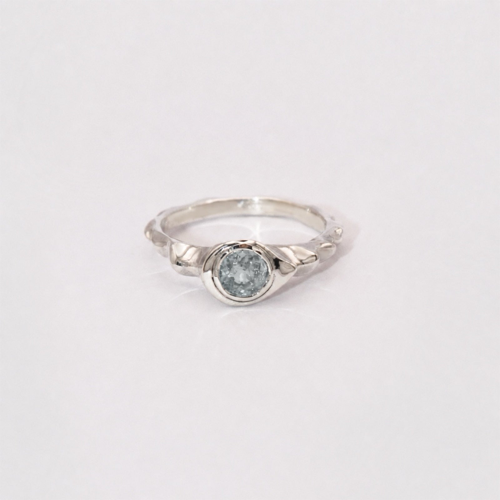 Silver ring with a light blue gemstone on a white background