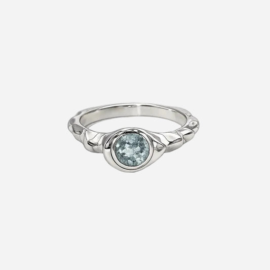 Silver ring with a blue gemstone on a black background