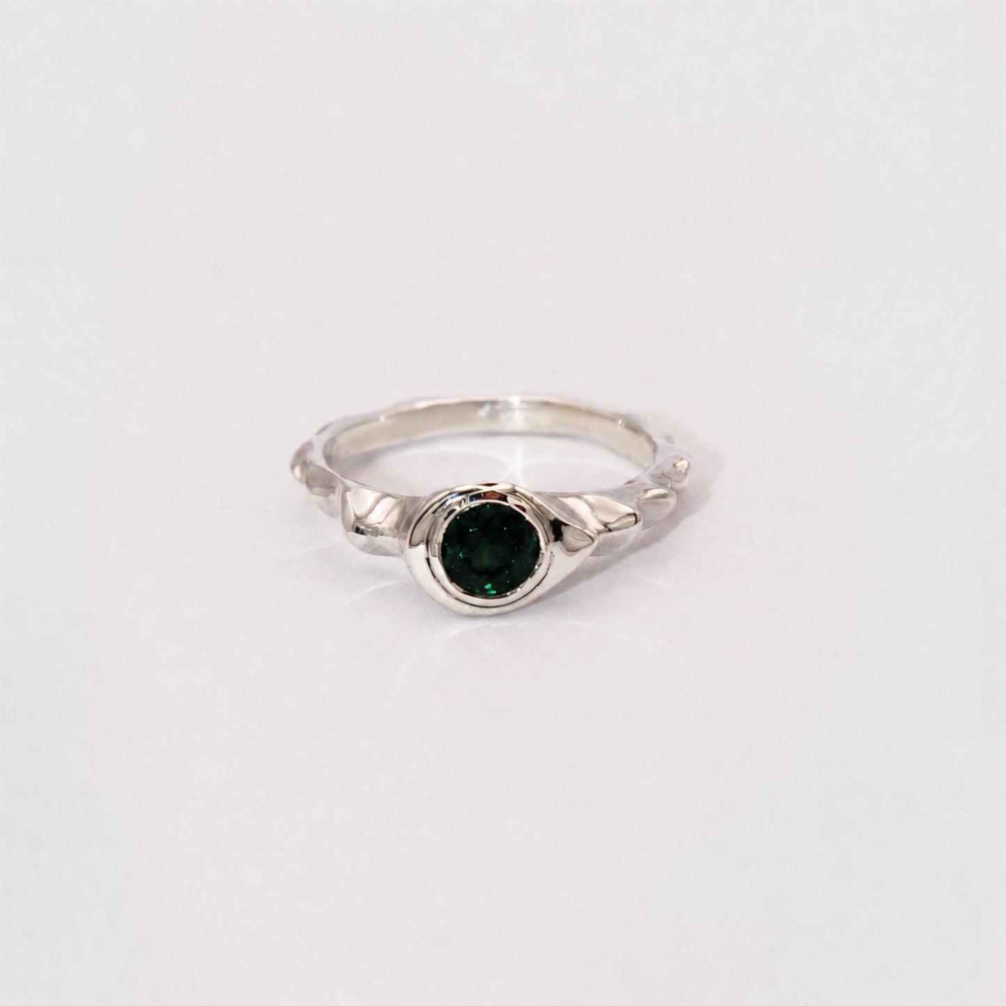 Silver ring with a green gemstone on a white background