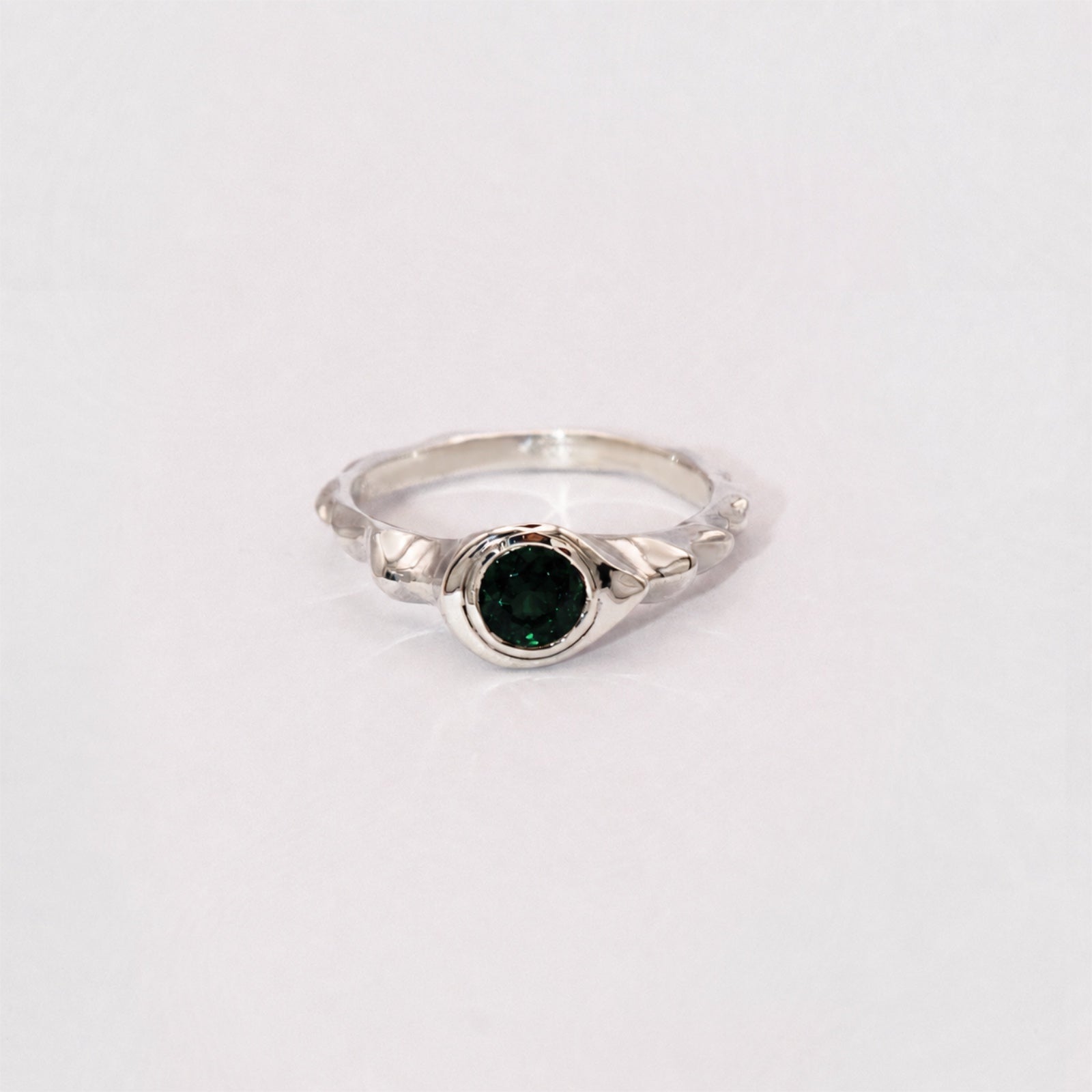 Silver ring with a green gemstone on a white background
