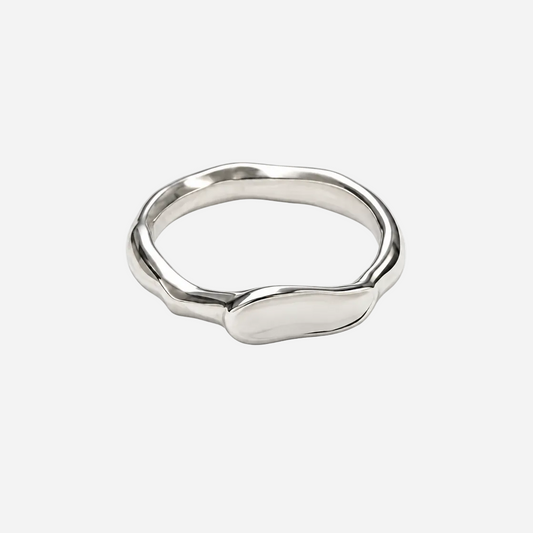 A polished silver ring with an organic, wavy, fluid silhouette, photographed on a seamless white background.