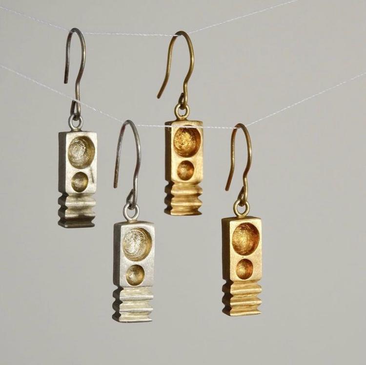 Pair of gold and silver earrings on a gray background