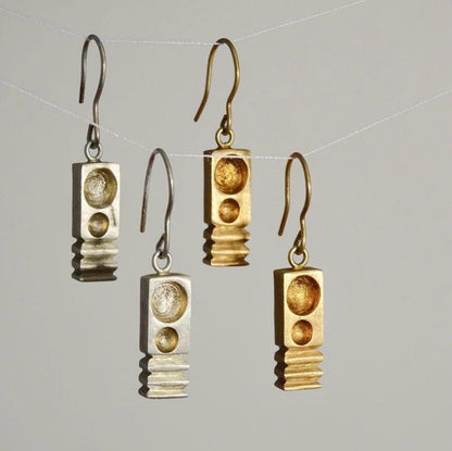 Pair of gold and silver earrings on a gray background