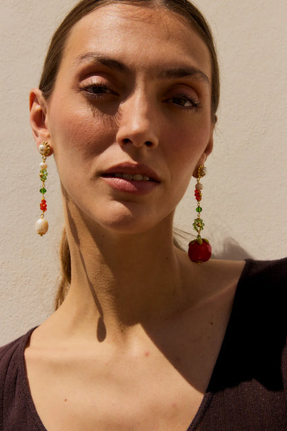 Woman wearing colorful earrings against a neutral background