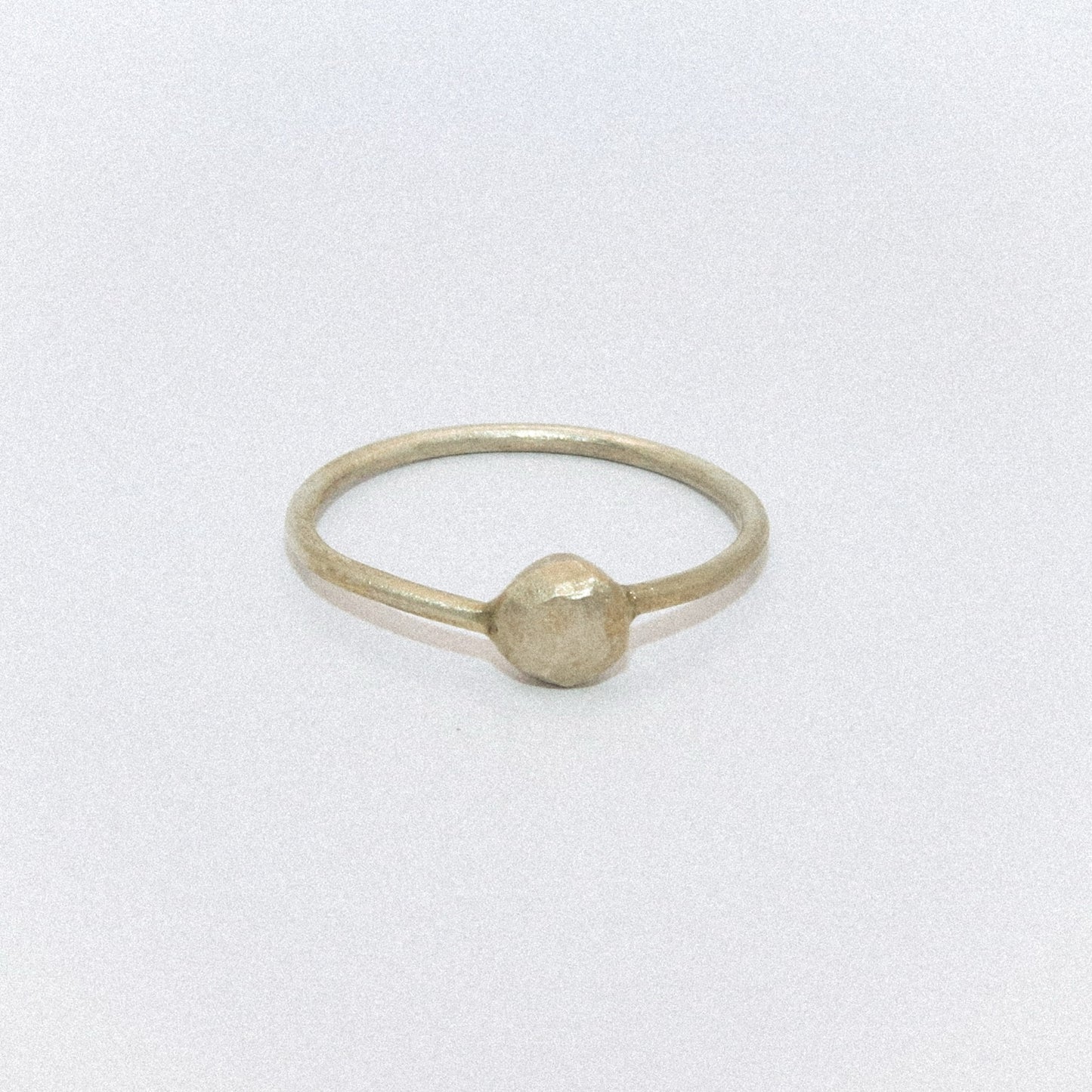 Gold ring with a round bead on a white background