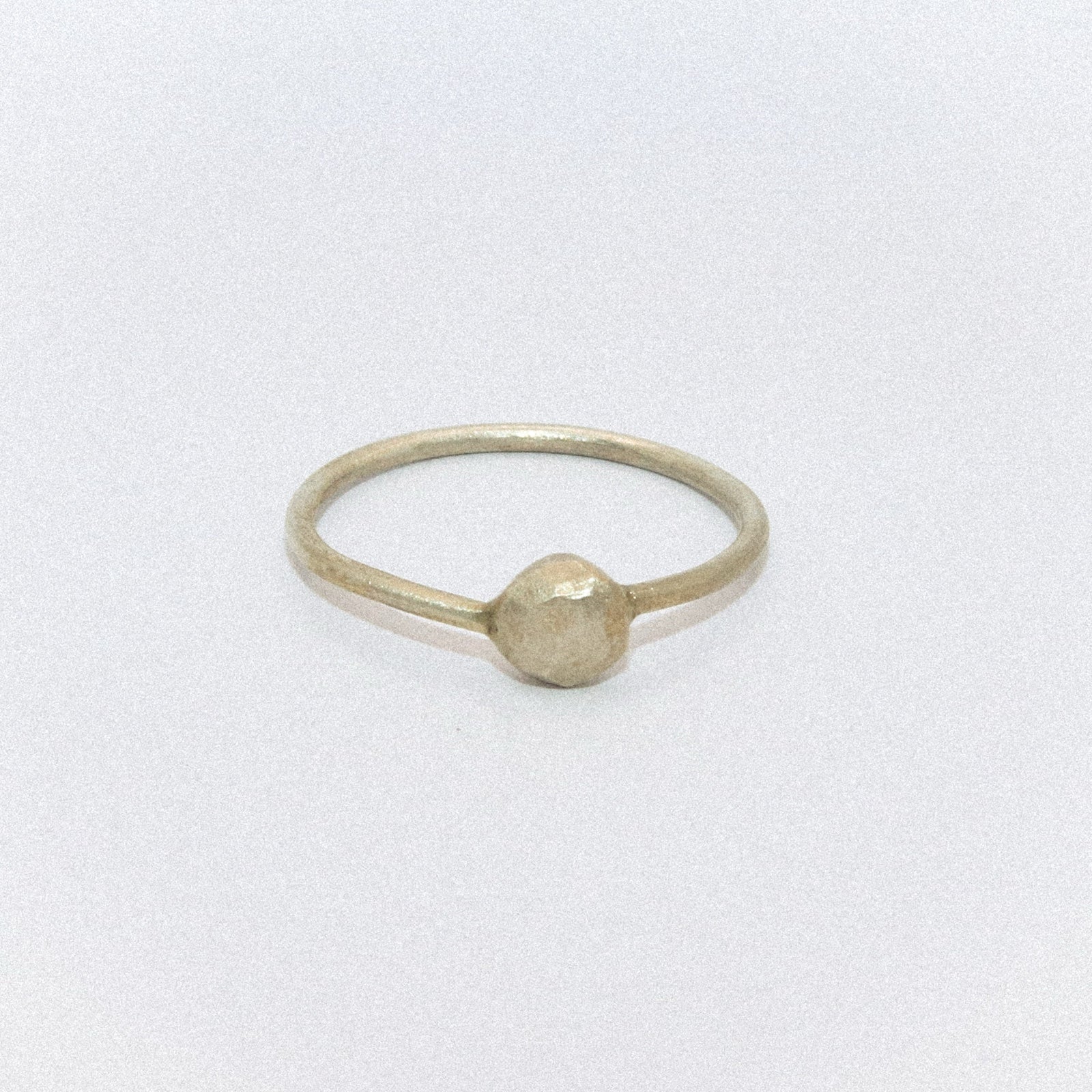 Gold ring with a round bead on a white background