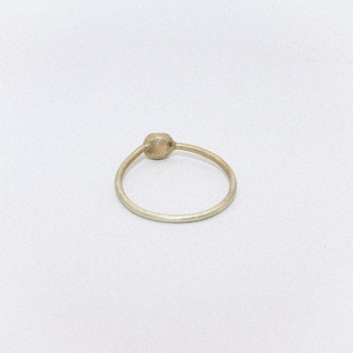 Gold ring with a small bead on a white background