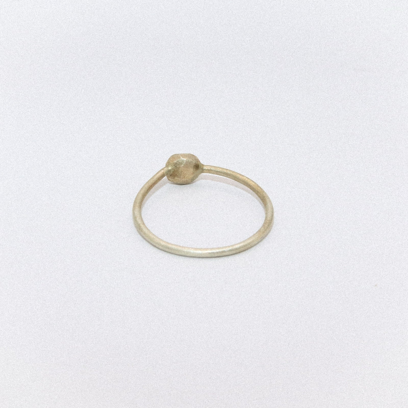 Gold ring with a small bead on a white background